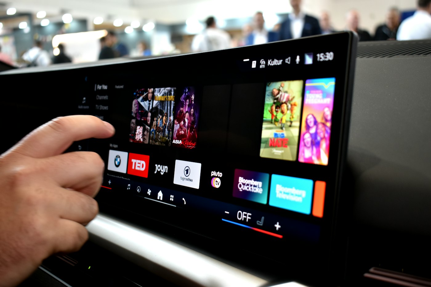 Person touching a car infotainment screen with media options.